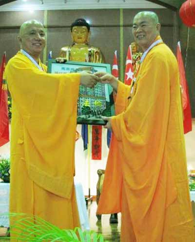 释日恒(右)赠送纪念品给承办单位马佛总柔佛分会会长释禅亮。