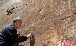 考古专家温玉成察看摩崖线刻长寿佛及二菩萨等造像。