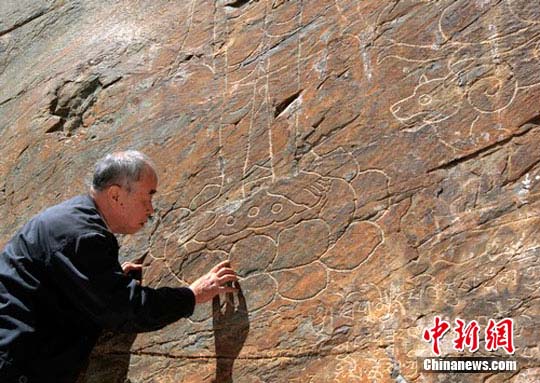 考古专家温玉成察看摩崖线刻长寿佛及二菩萨等造像。